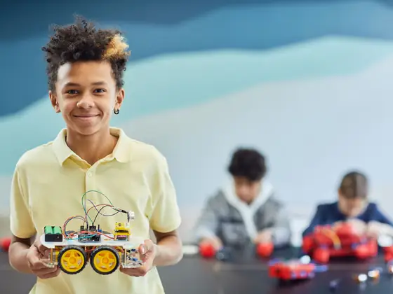 A boy proudly presenting the robot car he programmed