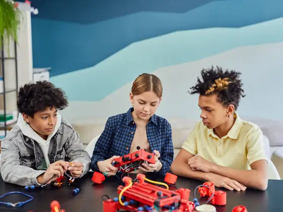 Children wiring an electronics circuit at a workbench