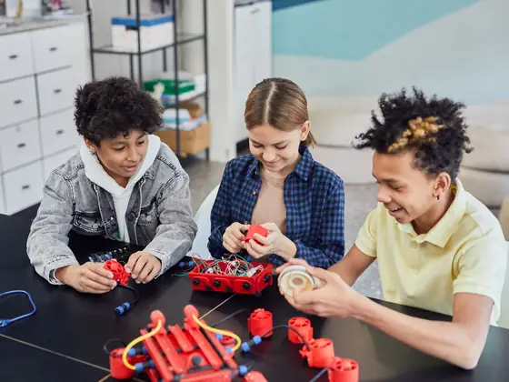 Young children laughing together as their robot moves across the table