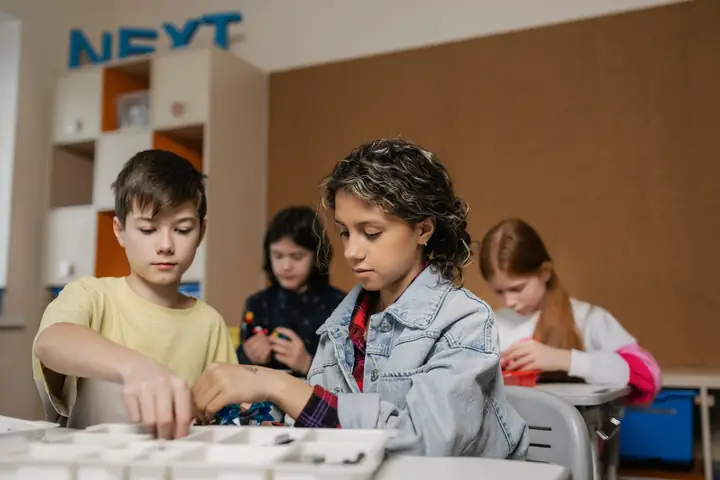 Teenagers assembling a robotics project together at a table, focused and enjoying it